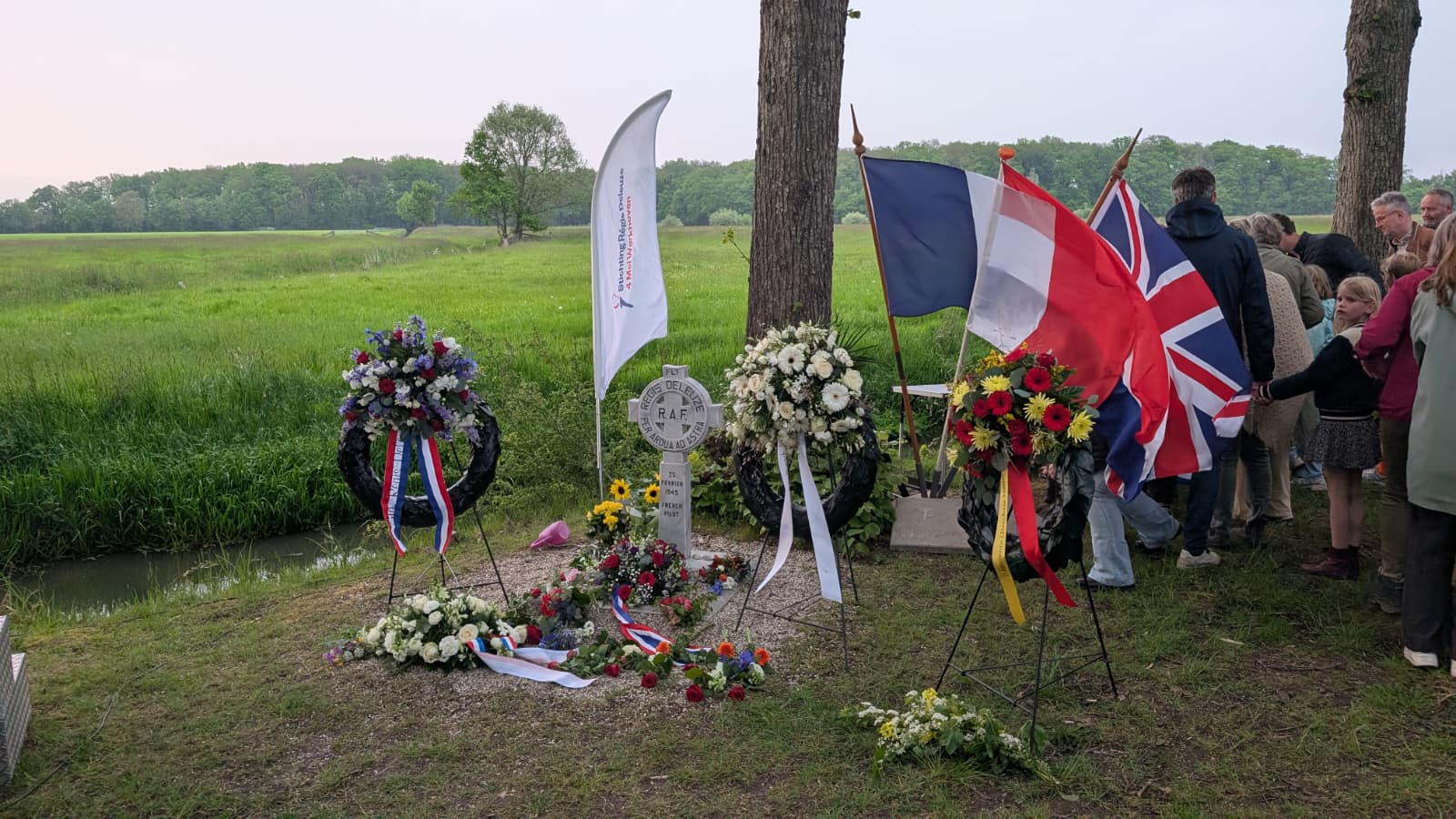 Monument voor Régis Deleuze in Werkhoven, met drie kransen met op de achtergrond de Franse, Nederlandse en Engelse vlag